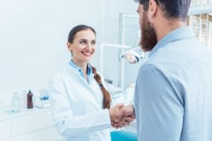 A dentist shaking hands with a patient